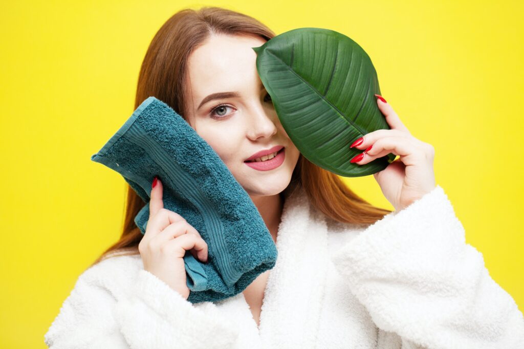 Young woman wipes face with soft towel after spa treatments